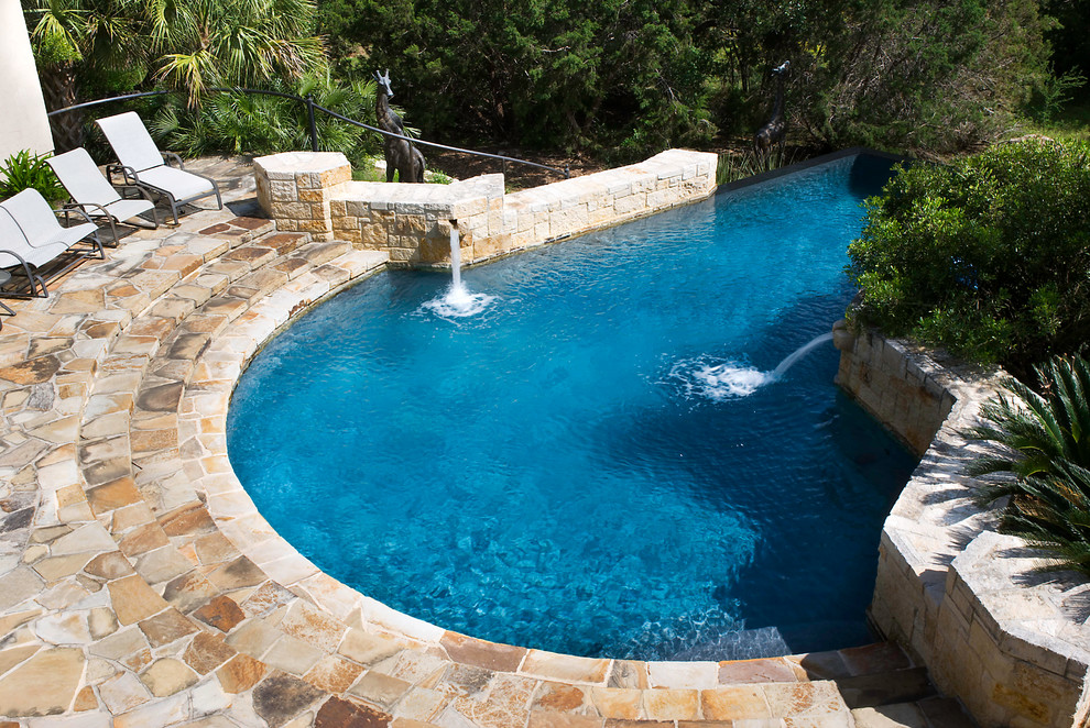 Design ideas for a large mediterranean back custom shaped infinity swimming pool in Austin with a water feature and natural stone paving.