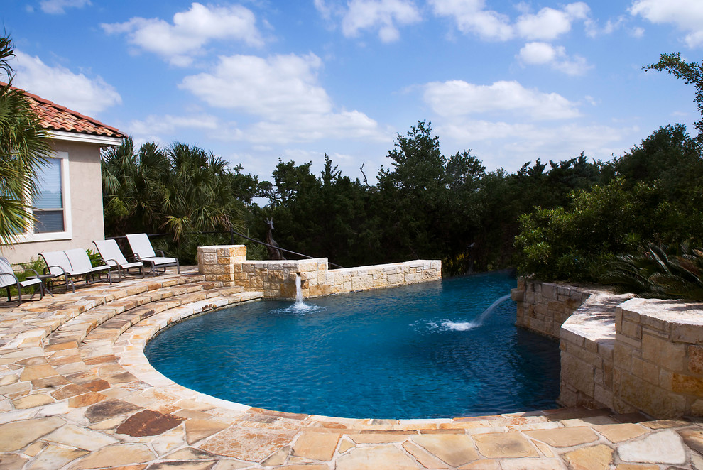 Pool fountain - large mediterranean backyard stone and custom-shaped infinity pool fountain idea in Austin