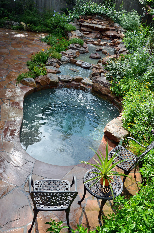 This is an example of a small rustic back custom shaped hot tub in Houston with natural stone paving.