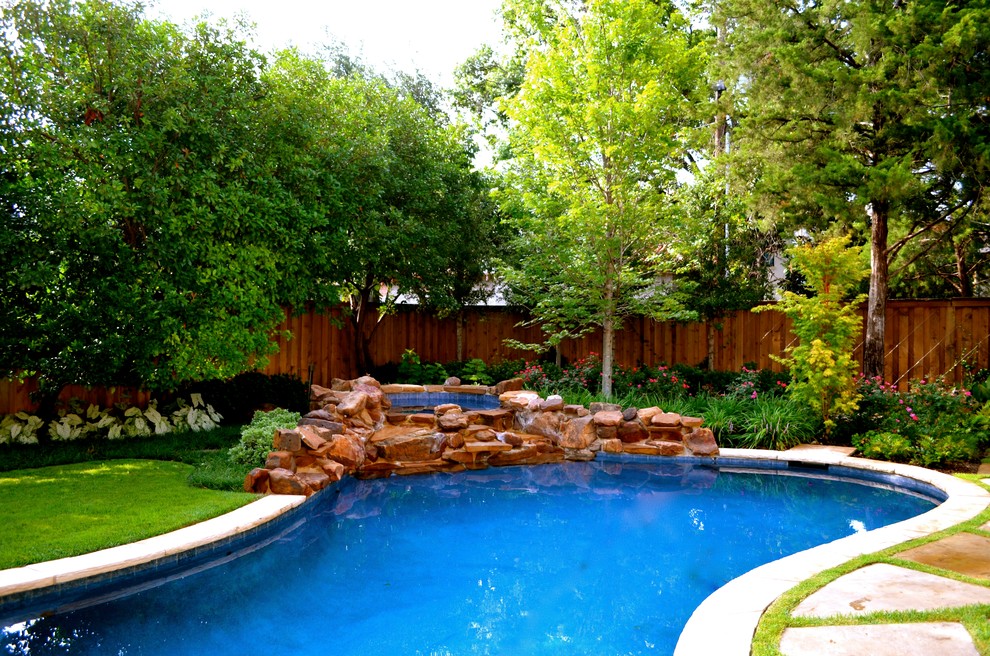 Immagine di una piscina tradizionale a "C" dietro casa e di medie dimensioni con fontane e pavimentazioni in pietra naturale