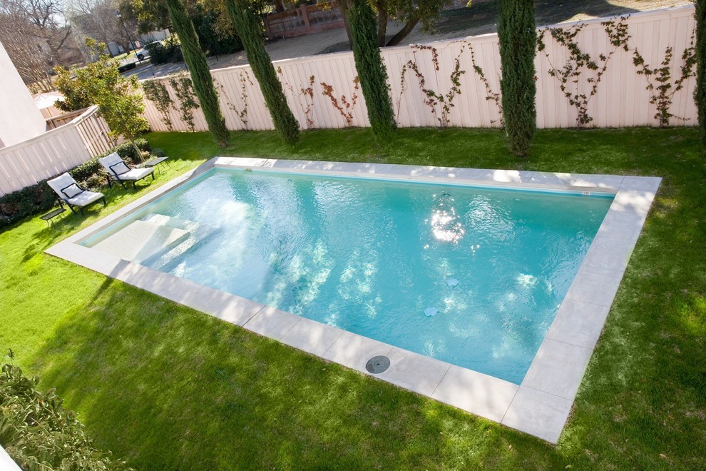 Ejemplo de piscina alargada clásica de tamaño medio rectangular en patio trasero con adoquines de hormigón