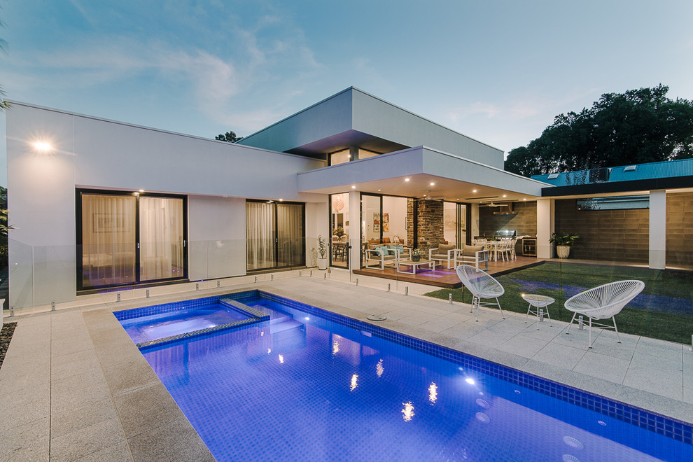 Esempio di una piscina monocorsia contemporanea rettangolare di medie dimensioni e dietro casa con una vasca idromassaggio e pavimentazioni in cemento