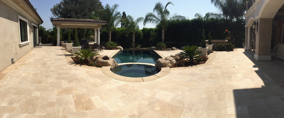 Foto di una grande piscina tradizionale personalizzata dietro casa con fontane e pavimentazioni in pietra naturale