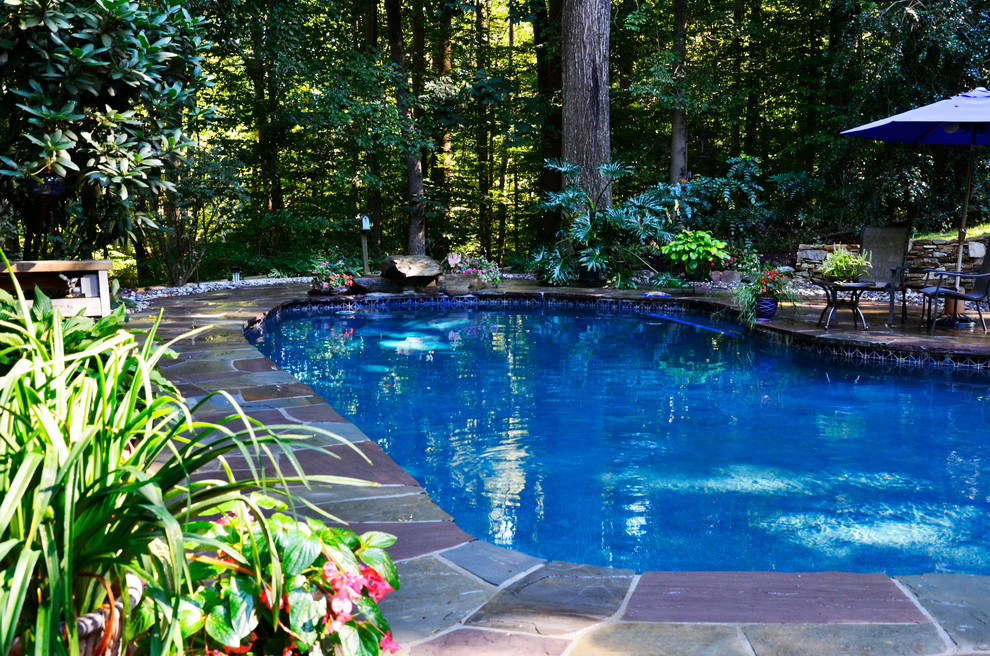 Foto de piscina grande tipo riñón en patio trasero con adoquines de piedra natural