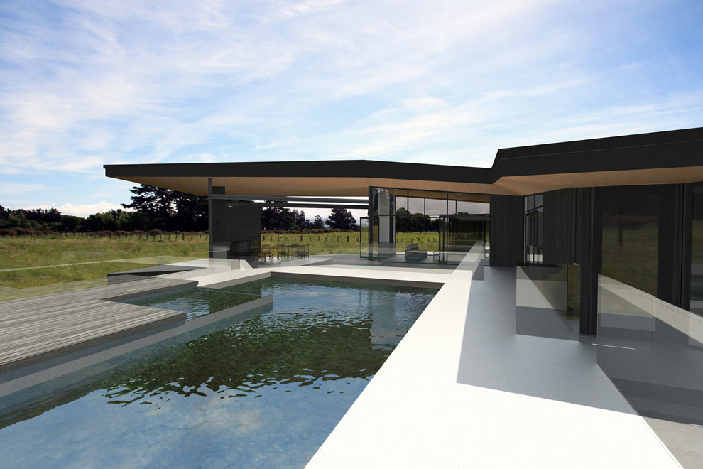 Идея дизайна: большой наземный бассейн произвольной формы на заднем дворе в стиле модернизм с покрытием из бетонных плит
