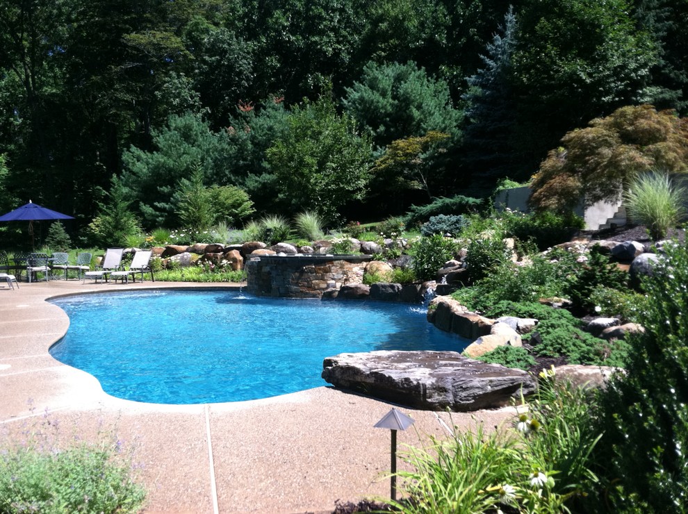 Imagen de piscina con fuente natural tradicional a medida en patio trasero con entablado