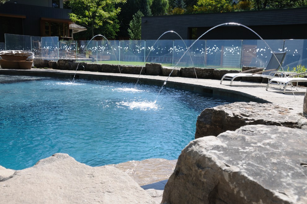 Esempio di una grande piscina minimalista dietro casa con fontane e pavimentazioni in pietra naturale