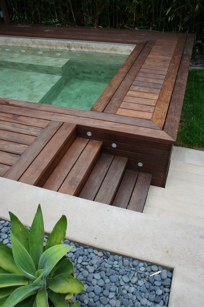 Inspiration pour une piscine design avec un bain bouillonnant et une terrasse en bois.
