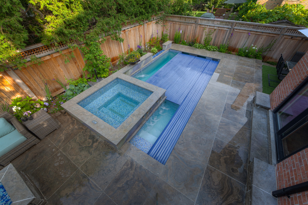 Imagen de piscina con fuente tradicional pequeña rectangular en patio trasero con adoquines de piedra natural