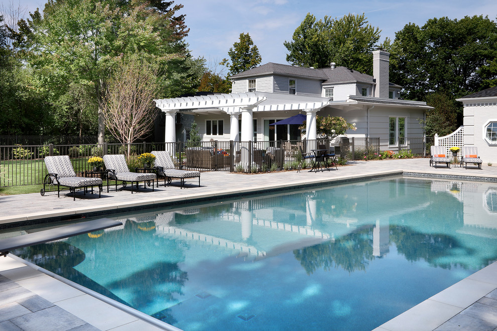 Diseño de piscina clásica extra grande rectangular en patio trasero con adoquines de piedra natural
