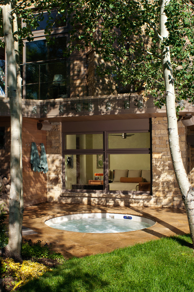 Источник вдохновения для домашнего уюта: большой круглый бассейн на заднем дворе в современном стиле с джакузи и покрытием из каменной брусчатки