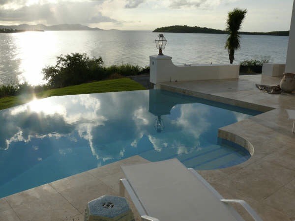 Esempio di una grande piscina a sfioro infinito tropicale personalizzata dietro casa con fontane e piastrelle