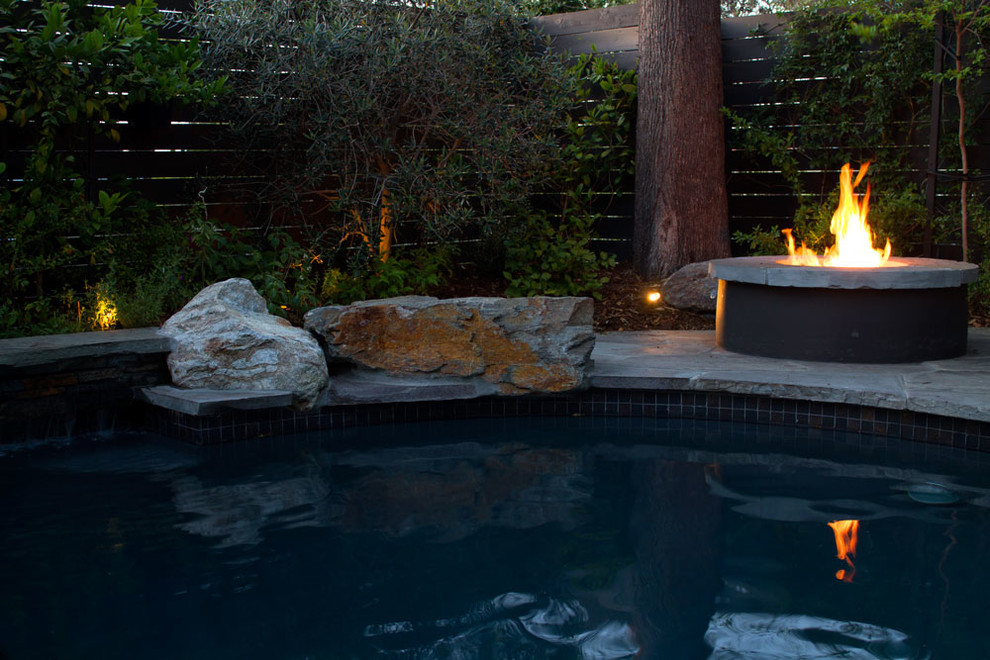 На фото: большой бассейн в форме фасоли на заднем дворе в стиле модернизм с фонтаном и покрытием из каменной брусчатки