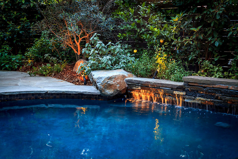 Foto di una grande piscina moderna a "C" dietro casa con pavimentazioni in pietra naturale