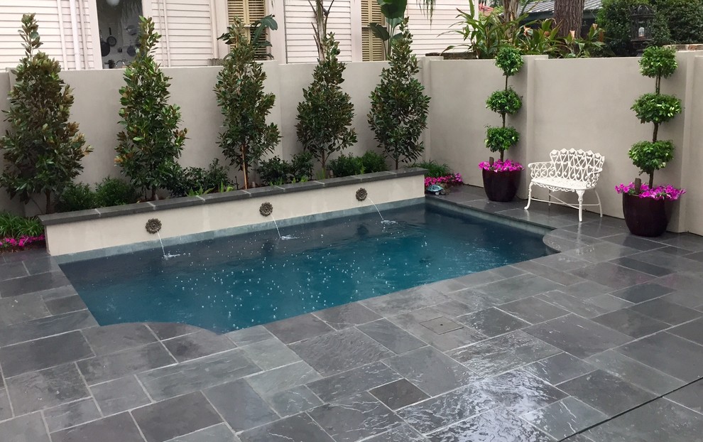 Immagine di una piscina monocorsia tradizionale rettangolare di medie dimensioni e dietro casa con fontane e pavimentazioni in pietra naturale