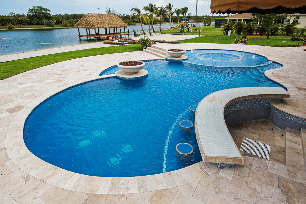 Ejemplo de piscinas y jacuzzis infinitos modernos grandes a medida en patio trasero con adoquines de piedra natural