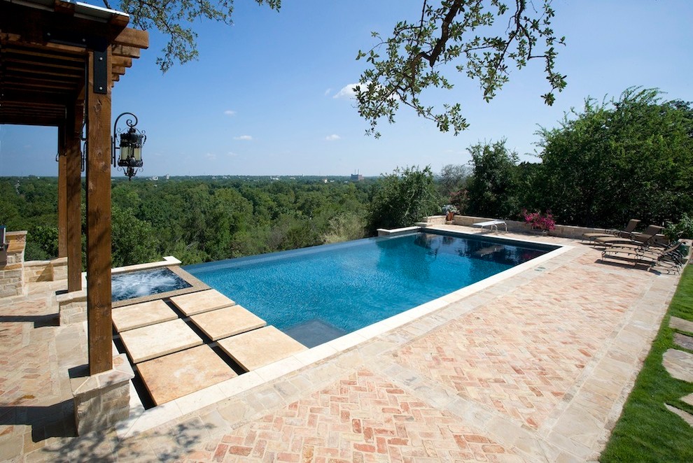 Modelo de piscinas y jacuzzis infinitos tradicionales de tamaño medio rectangulares en patio trasero con adoquines de ladrillo