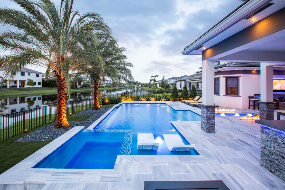 Großer Moderner Infinity-Pool hinter dem Haus in individueller Form mit Pool-Gartenbau und Natursteinplatten in Miami