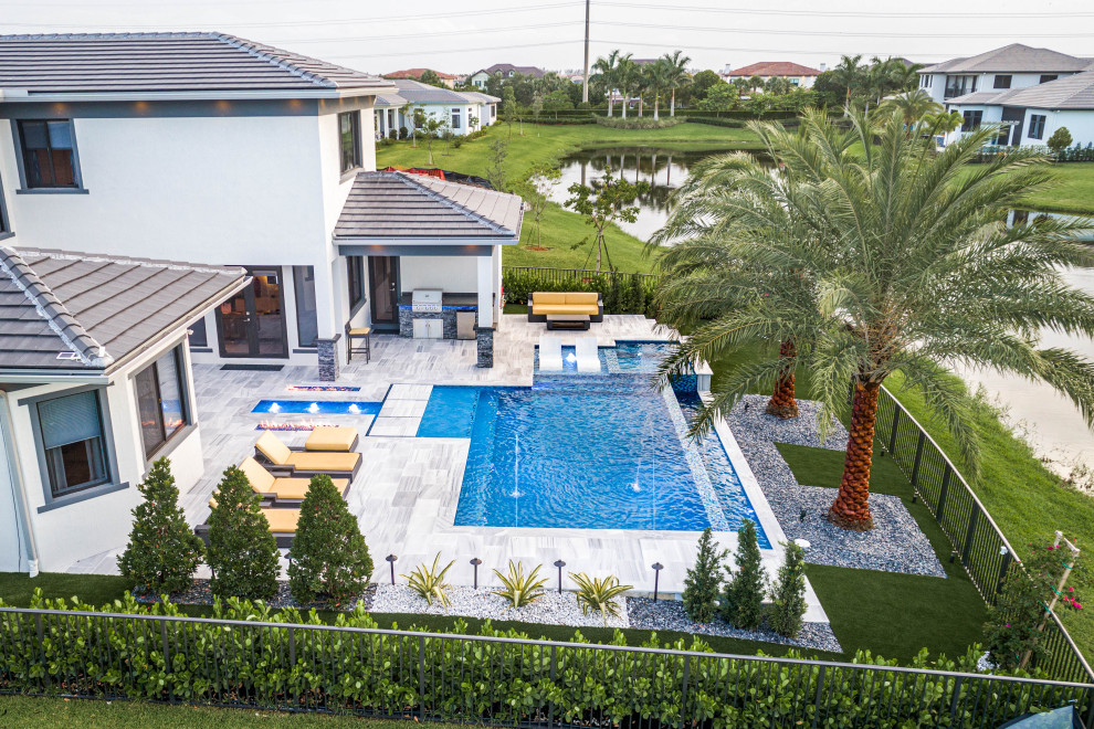 Large minimalist backyard stone and custom-shaped infinity pool landscaping photo in Miami