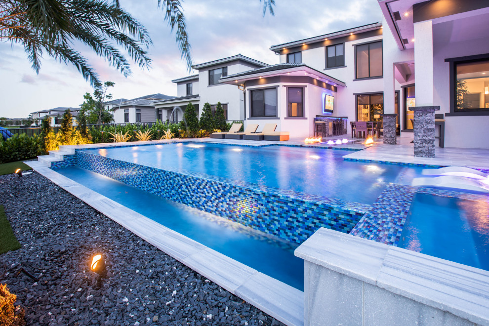 Идея дизайна: большой бассейн произвольной формы на заднем дворе в стиле модернизм с покрытием из каменной брусчатки