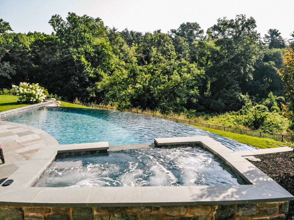 Esempio di una piscina a sfioro infinito chic personalizzata di medie dimensioni e dietro casa con fontane e pavimentazioni in pietra naturale