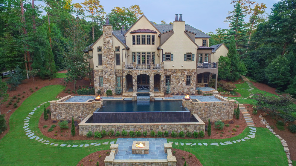 Inspiration for a large tropical backyard stone and custom-shaped infinity pool fountain remodel in Atlanta