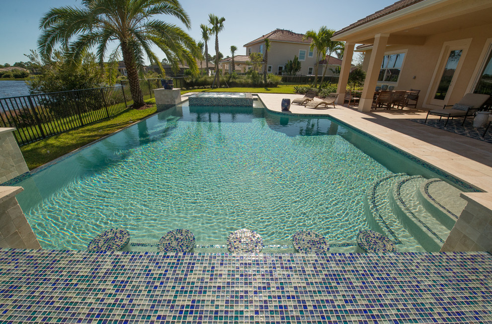 Idee per una piscina a sfioro infinito minimalista personalizzata di medie dimensioni e dietro casa con pavimentazioni in pietra naturale