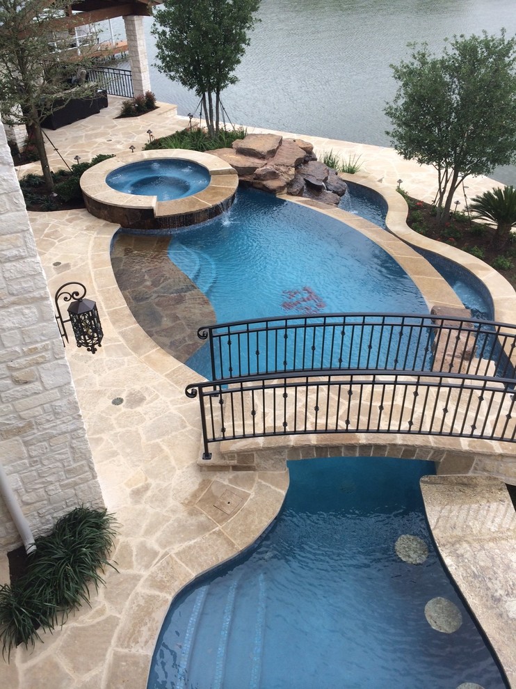 Foto di una grande piscina a sfioro infinito classica personalizzata dietro casa con una vasca idromassaggio