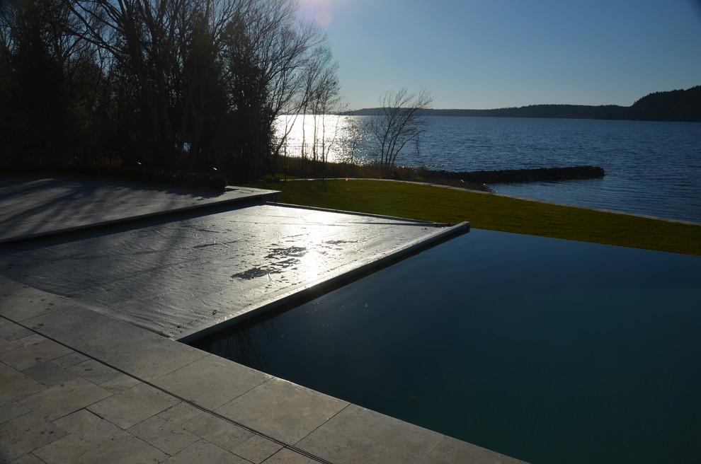 Großer Moderner Infinity-Pool hinter dem Haus in rechteckiger Form mit Natursteinplatten in Sonstige