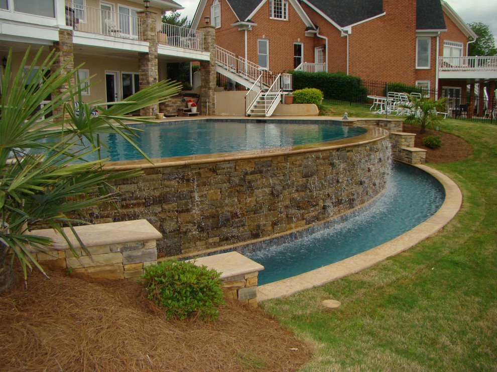 Immagine di una piscina a sfioro infinito classica personalizzata dietro casa con fontane