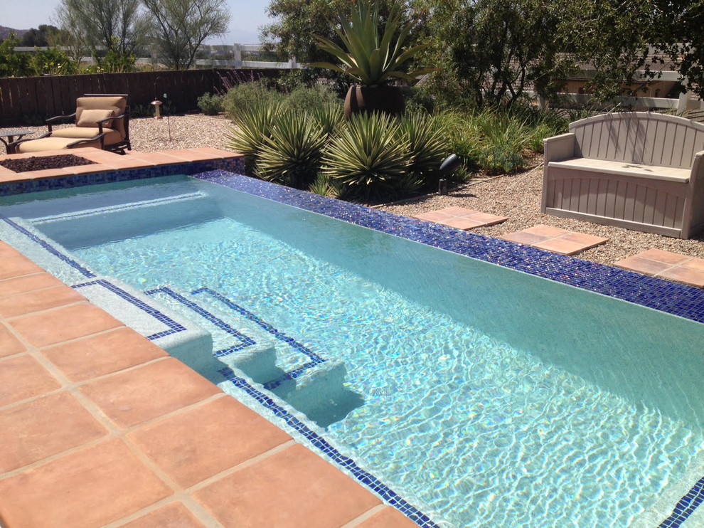Immagine di una piscina a sfioro infinito american style rettangolare di medie dimensioni e dietro casa con una vasca idromassaggio e piastrelle