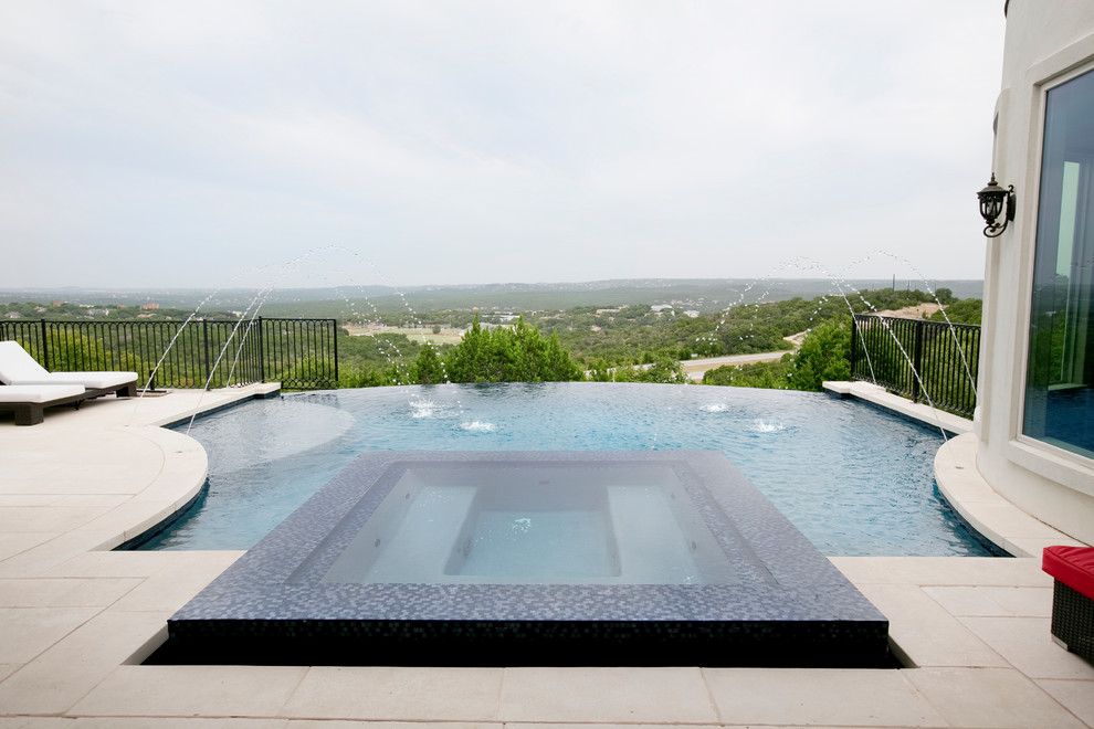 Ejemplo de piscina con fuente infinita contemporánea grande a medida en patio trasero con adoquines de hormigón