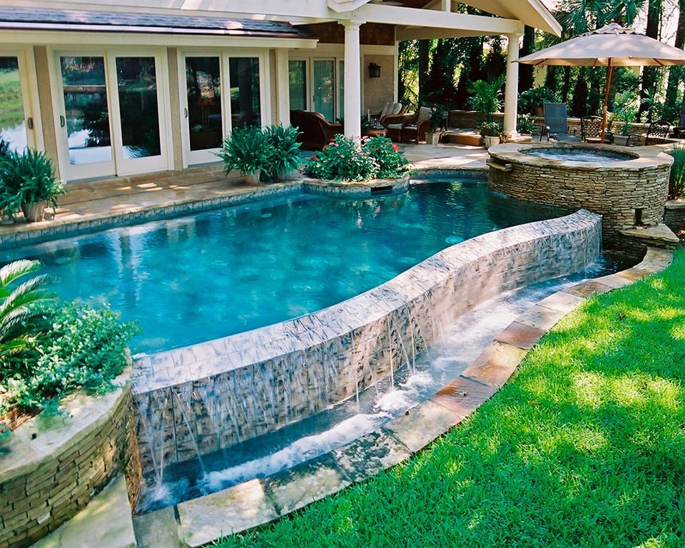 Modelo de piscinas y jacuzzis infinitos de tamaño medio a medida en patio trasero con suelo de baldosas