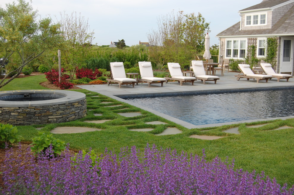 Ejemplo de piscina clásica rectangular en patio trasero con adoquines de piedra natural