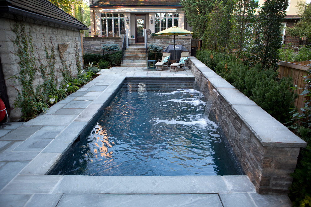 Esempio di una piccola piscina monocorsia tradizionale rettangolare dietro casa con fontane e pavimentazioni in pietra naturale