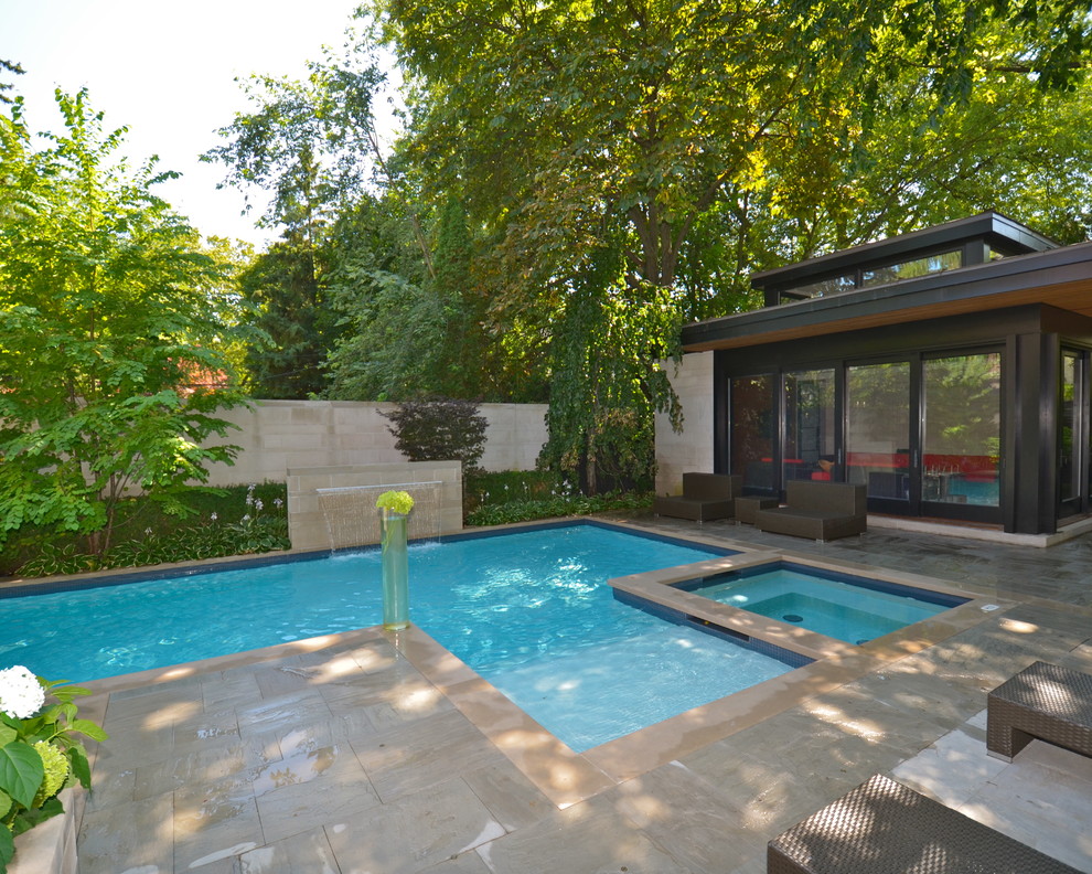Esempio di una grande piscina minimalista rettangolare dietro casa con fontane e pavimentazioni in pietra naturale