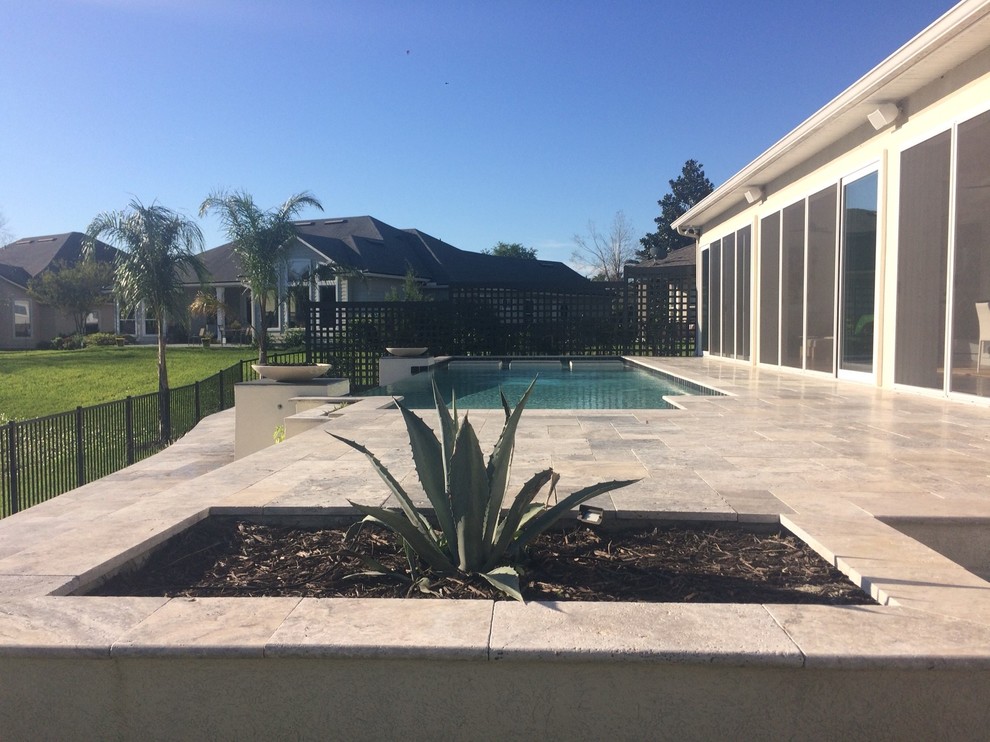 Foto de piscina infinita clásica renovada grande rectangular en patio trasero con suelo de baldosas