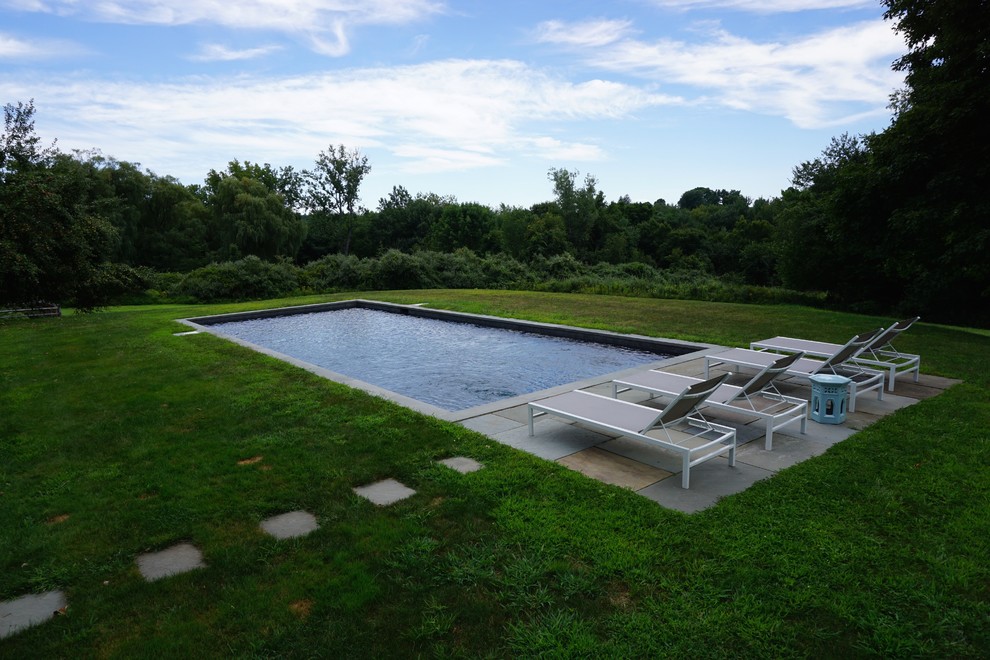 Medium sized modern back rectangular lengths swimming pool in New York with concrete slabs.