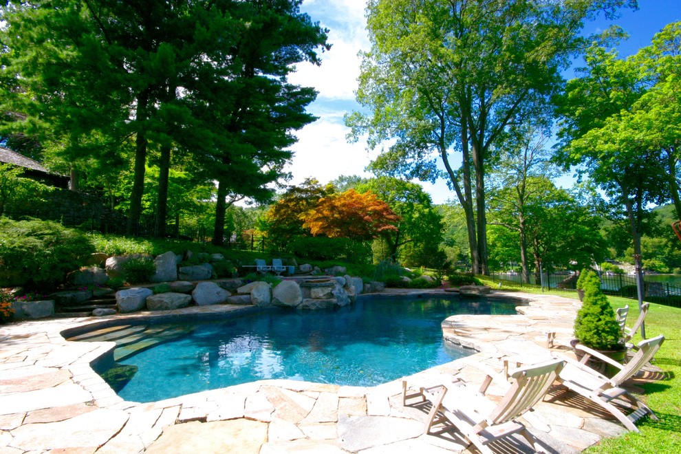 Diseño de piscina natural minimalista grande a medida en patio trasero con adoquines de piedra natural