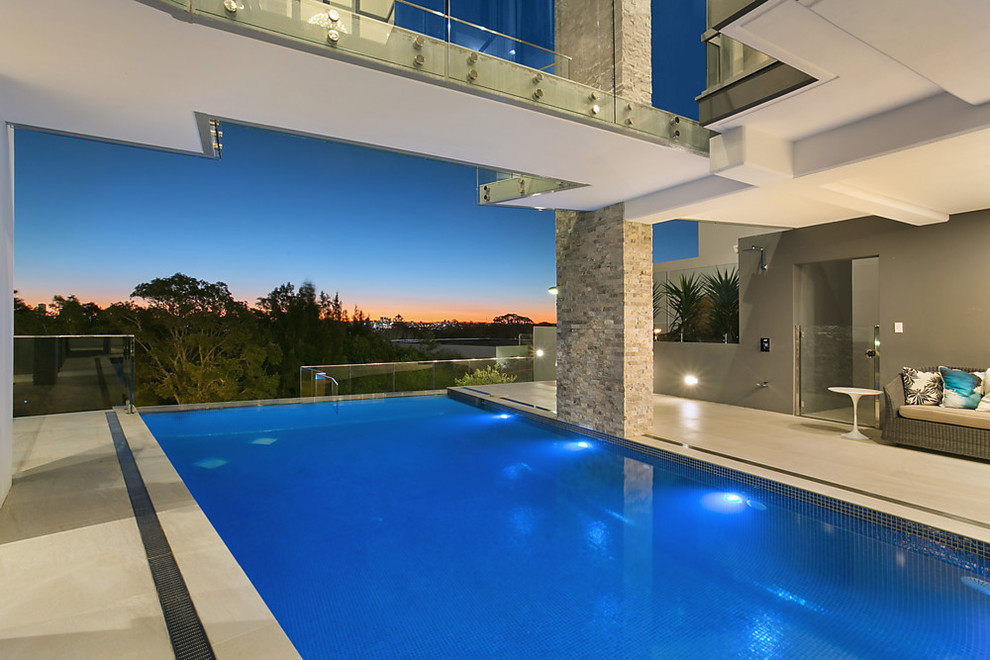 Esempio di un'ampia piscina monocorsia contemporanea rettangolare dietro casa con fontane e pavimentazioni in pietra naturale