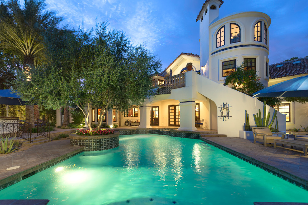 Immagine di una piscina naturale mediterranea personalizzata di medie dimensioni e dietro casa con piastrelle