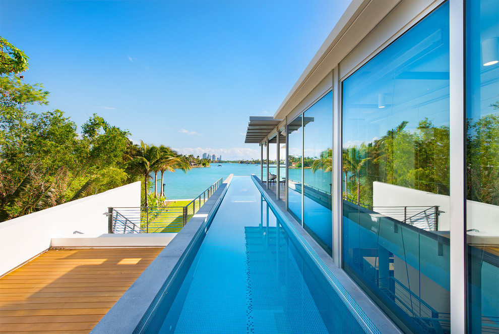 Diseño de piscina alargada actual extra grande rectangular en patio lateral con entablado