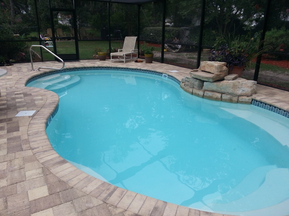 Foto de piscina con fuente de tamaño medio tipo riñón en patio trasero con adoquines de ladrillo