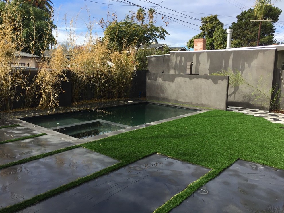 Immagine di una piscina monocorsia minimalista rettangolare di medie dimensioni e dietro casa con una vasca idromassaggio e pavimentazioni in cemento