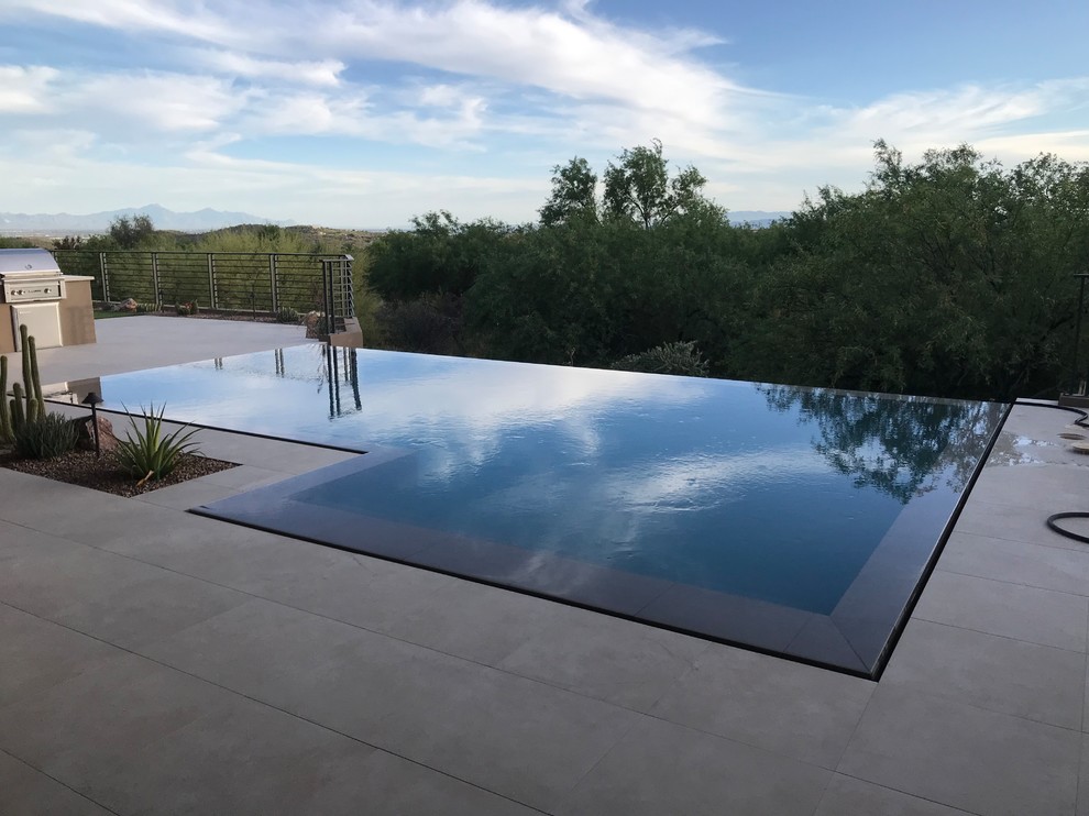 Imagen de piscina infinita minimalista de tamaño medio a medida en patio trasero con adoquines de piedra natural