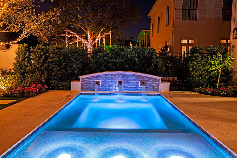 Photo of a small classic front rectangular swimming pool in Houston with a water feature and natural stone paving.