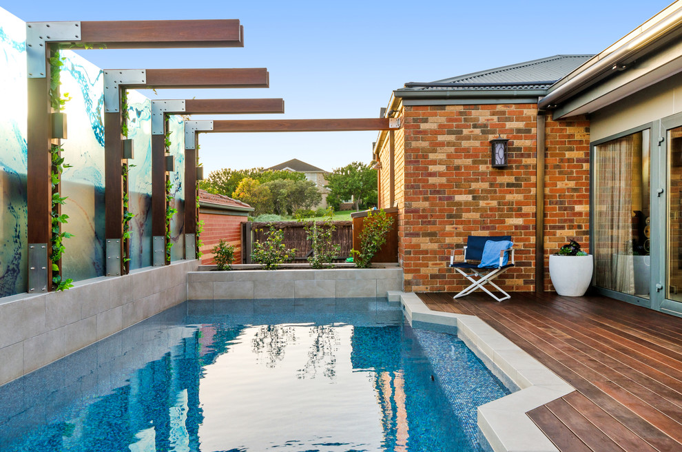 Aménagement d'une piscine à débordement contemporaine de taille moyenne et rectangle avec une cour et une terrasse en bois.