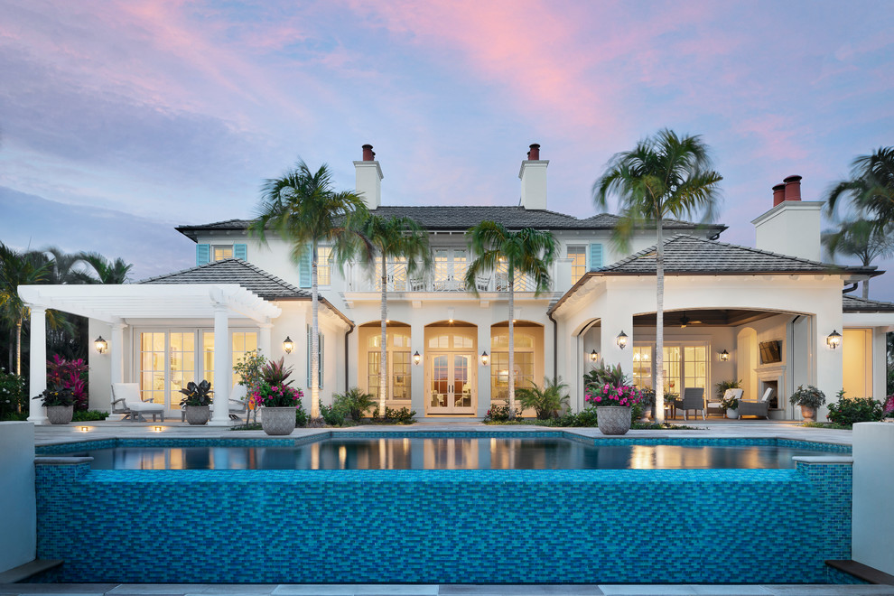 Foto di una grande piscina a sfioro infinito costiera rettangolare dietro casa con fontane e piastrelle