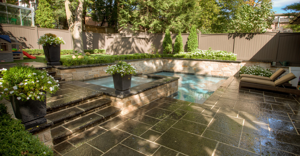 Modelo de piscinas y jacuzzis alargados tradicionales de tamaño medio a medida en patio trasero con adoquines de piedra natural