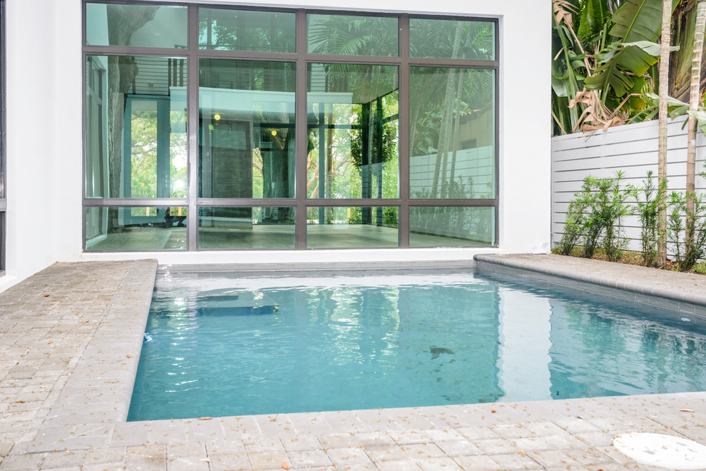 Esempio di una piscina moderna rettangolare di medie dimensioni e dietro casa con lastre di cemento